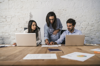 Three people working together looking over documents