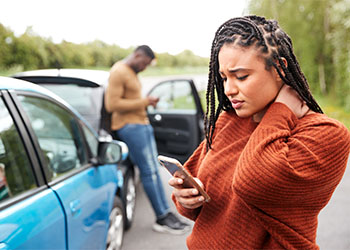 Woman using phone after car accident