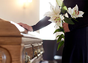 Woman with lily flowers and coffin at funeral