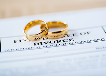 Two broken golden wedding rings with divorce decree document