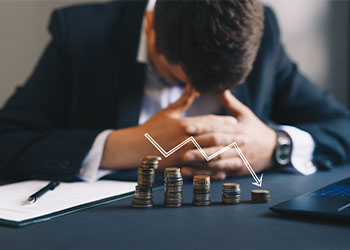 Stack of coins in descending order and depressed businessman