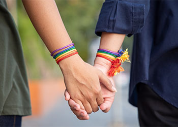 Women holding hands with rainbow ribbon symbol