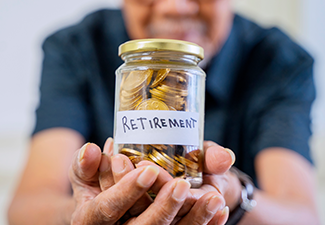 Elderly man hand showing a jar full of saving coins