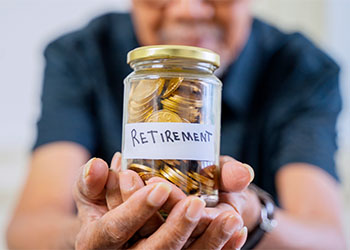 Retirement written on a jar of coins held by old man