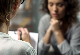 Young depressed woman talking to lady psychologist during session