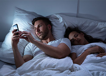 Man texting on phone while wife is sleeping