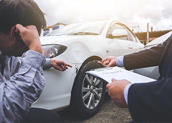 Insurance agent examining car after accident