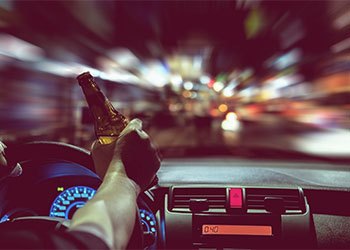 Man driving at night while drinking beer