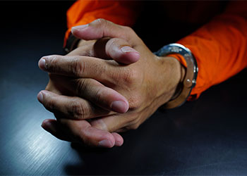 Prisoner's hands handcuffed in a dark room