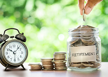 Coin filled jar labelled as Retirement with retro alarm clock