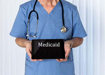 Doctor carrying tablet with word Medicaid