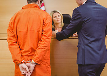 Lawyer and judge speaking next to the criminal in handcuffs