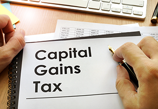 Hands Holding Documents with Title Capital Gains Tax