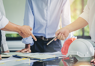 Contractor and engineer with blueprints discuss at a modern construction site