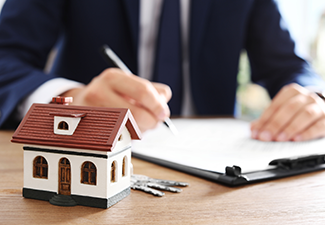 House model and blurred real estate agent on background