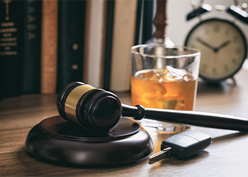 Law gavel, alcohol and car keys on a wooden desk