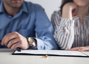 Couple with divorce contract and ring on desk