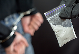 Police holding packet of drug after putting person with handcuffs