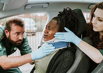 Paramedic placing a cervical collar to an injured woman 