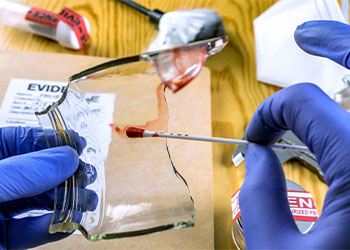 Police expert gets blood sample from a broken glass