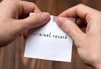 Hands of a man tearing a piece of paper with inscription criminal record