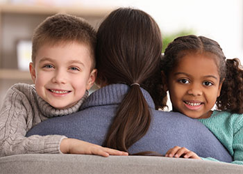 Woman hugging little kids of different ethnicity, adoption concept