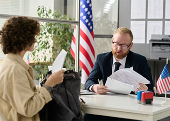 Man reviewing documents of young women in US Immigration office