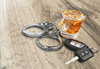 Whiskey with car keys and handcuffs on table