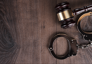 Handcuffs and judge gavel on wooden background