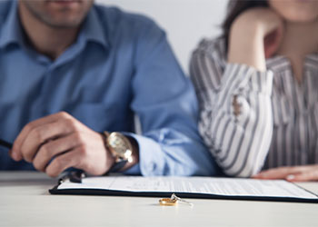 Couple with divorce contract and ring on desk