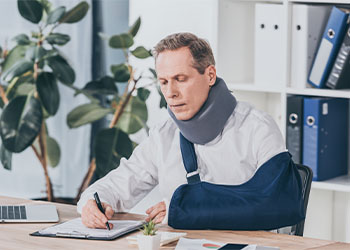 Man with neck brace and arm brace filling in form