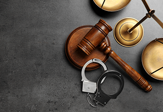 Judge's gavel, handcuffs and scales on grey background