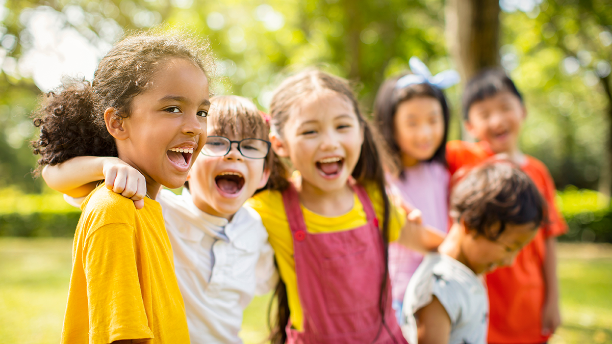 A diverse group of children laughing in a park.
