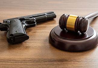 Judge gavel and handgun on table, close up