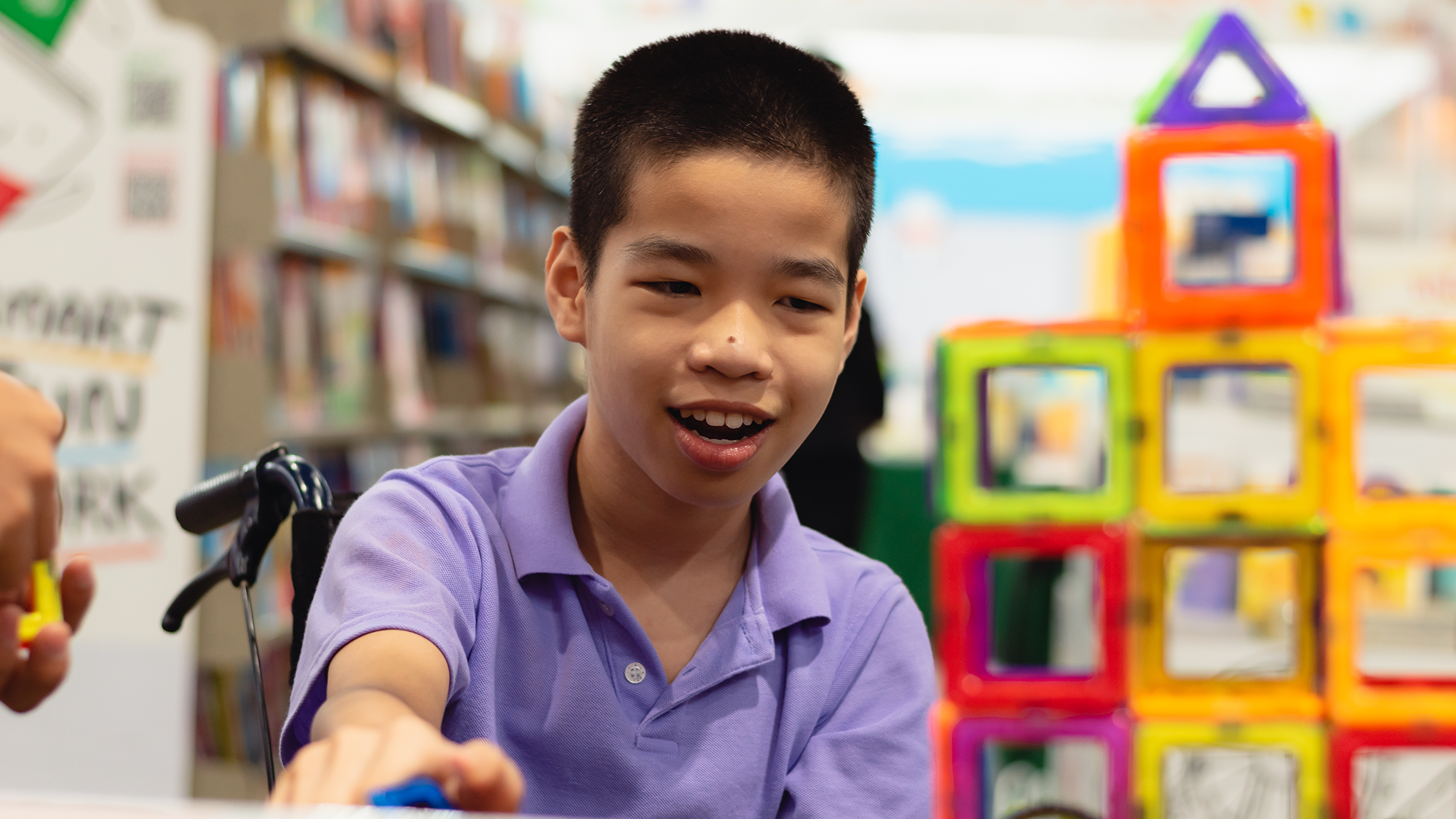 A special needs child in a wheelchair using building tiles.