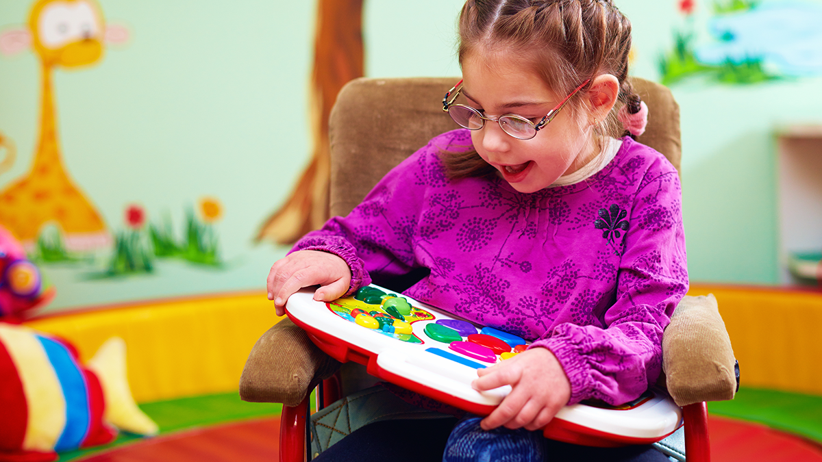 A special needs girl playing with a toy.