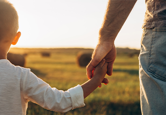 Father's and his son holding hands at sunset field