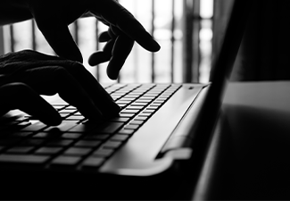 Cyber criminal hand reaching, stealing information on laptop
