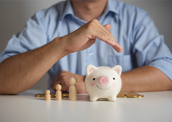Man protecting piggy bank under hand