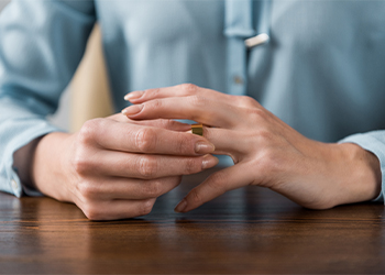 Partial view of woman taking off wedding ring