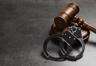 Judge's gavel and handcuffs on grey background