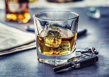 Car keys and glass of alcohol on table