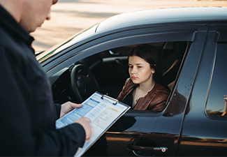 Policeman in uniform stopping a car driver to check her documents