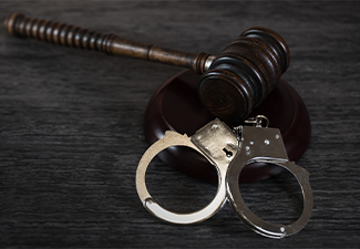 Handcuffs and gavel on dark rustic table