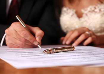 Groom and bride carefully reviewing and signing prenuptial agreement