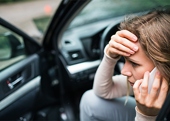 Stressed woman making phone call after car accident
