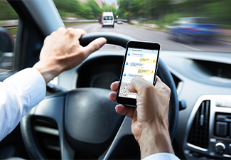 Man Typing Text Message On Mobile Phone While Driving Car