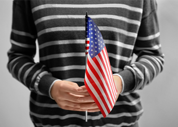 Woman holding American flag on light background