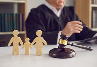 Gavel and small wooden figurines of husband, wife and kid on judge's table