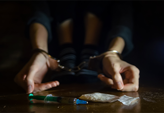 Man sitting on the floor and his hands locked in handcuffs